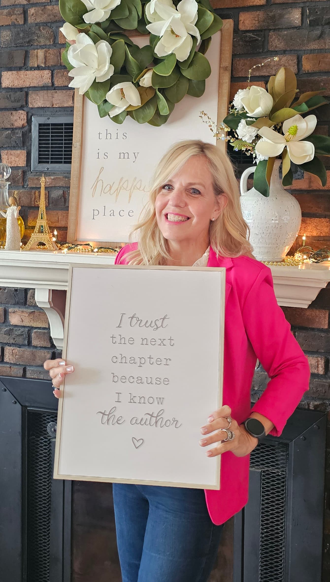 Lisa Ann Morrison smiling in a pink blazer and holding a framed message about trusting the next chapter